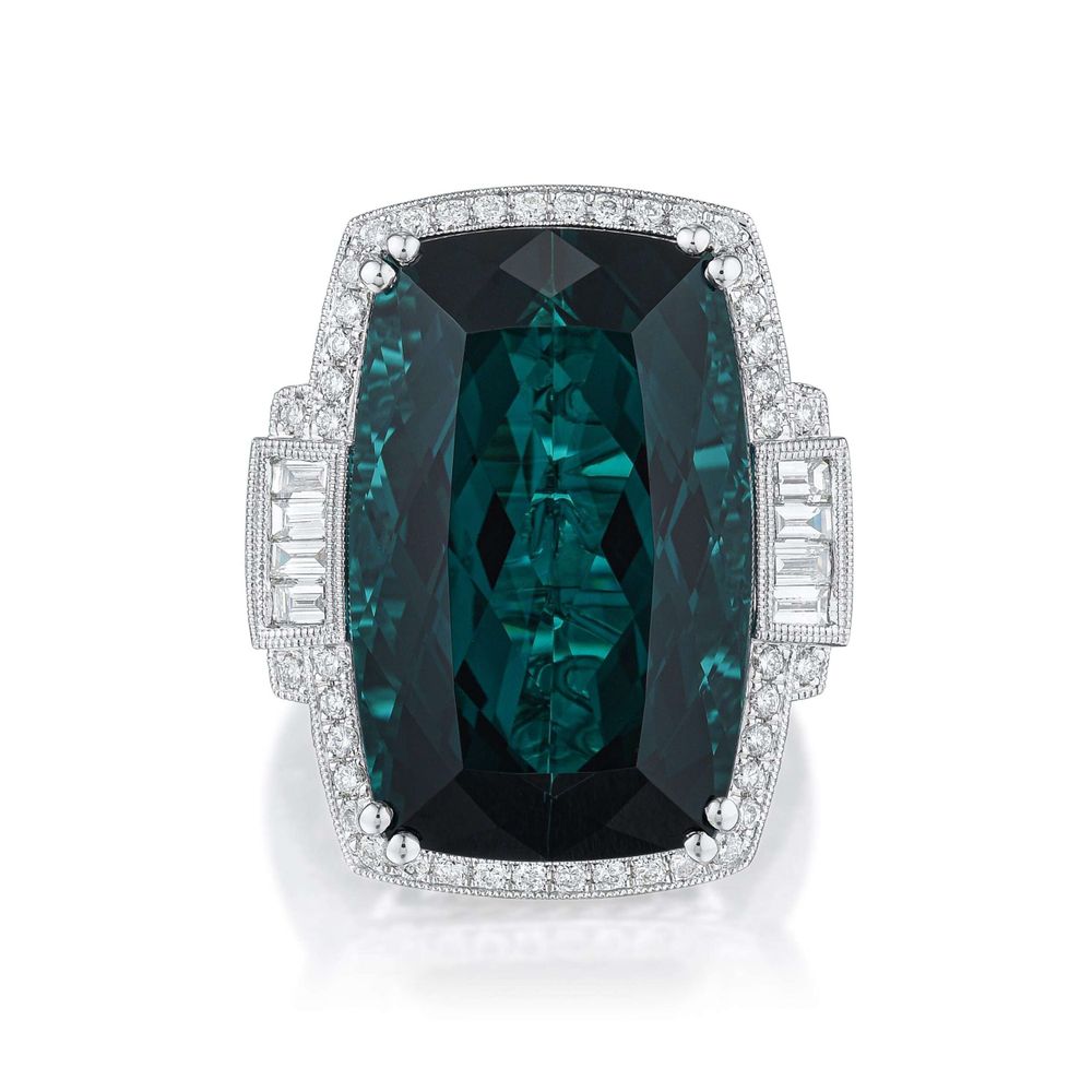 A faceted indicolite stone set in a ring, surrounded by small diamonds.