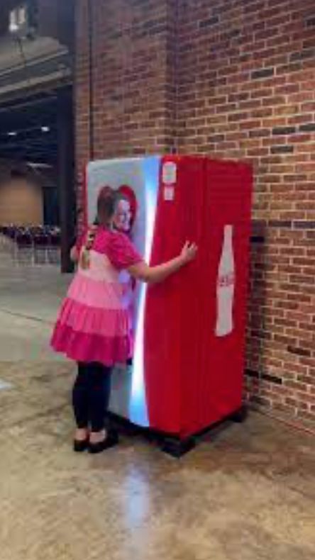 A woman hugging a diet coke machine