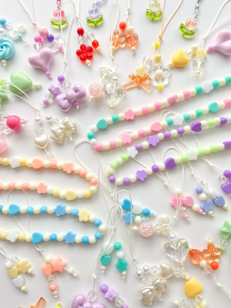An assortment of colorful beaded charms arranged on a white surface, featuring various shapes like hearts and flowers.