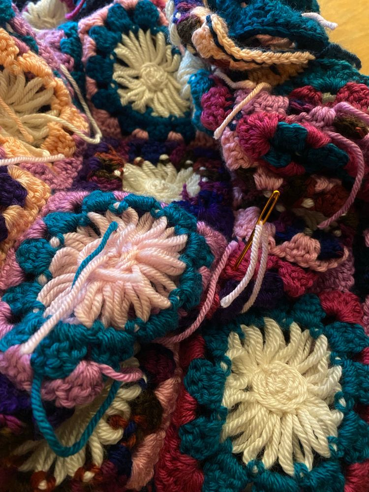 Colour photograph: The inside of a granny square cardigan is shown piled on a table. There are many loose ends of thread sticking out haphazardly. 