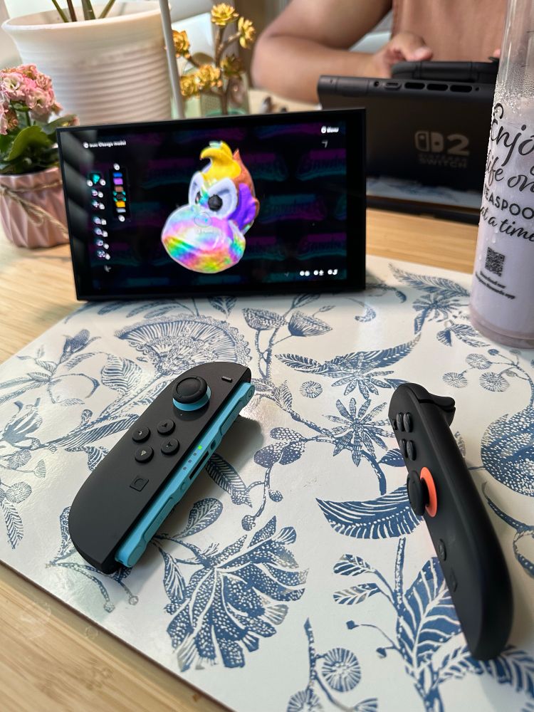 Switch 2 sitting on table with badly painted Donkey Kong on screen. Two switch joycons sit in front of it.