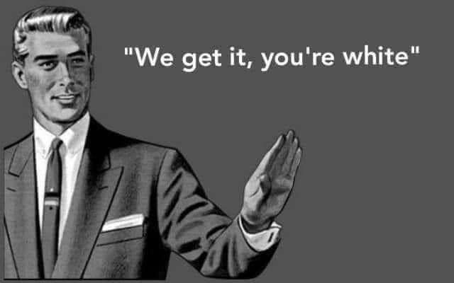 White man in suit smiles and holds up his palm as if to ward off further explanations or excuses as he says, "We get it, you're white."