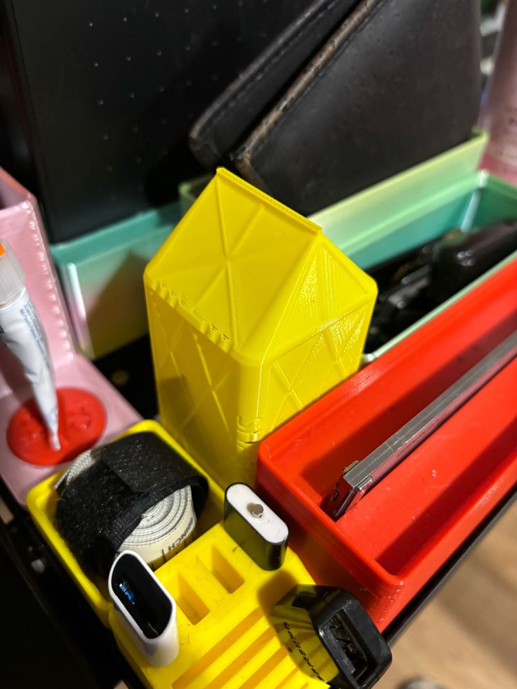 A yellow box, that looks like a mini milk carton sits alongside other plastic organizers.