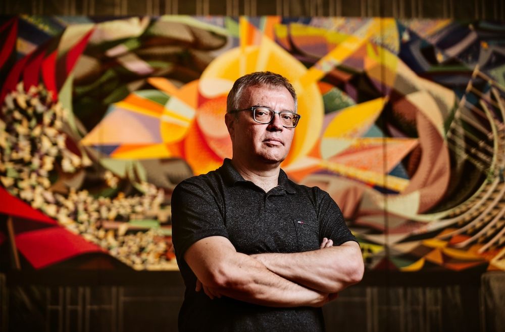 Le réalisateur Daniel Monzon, les bras croisés devant une fresque colorée.