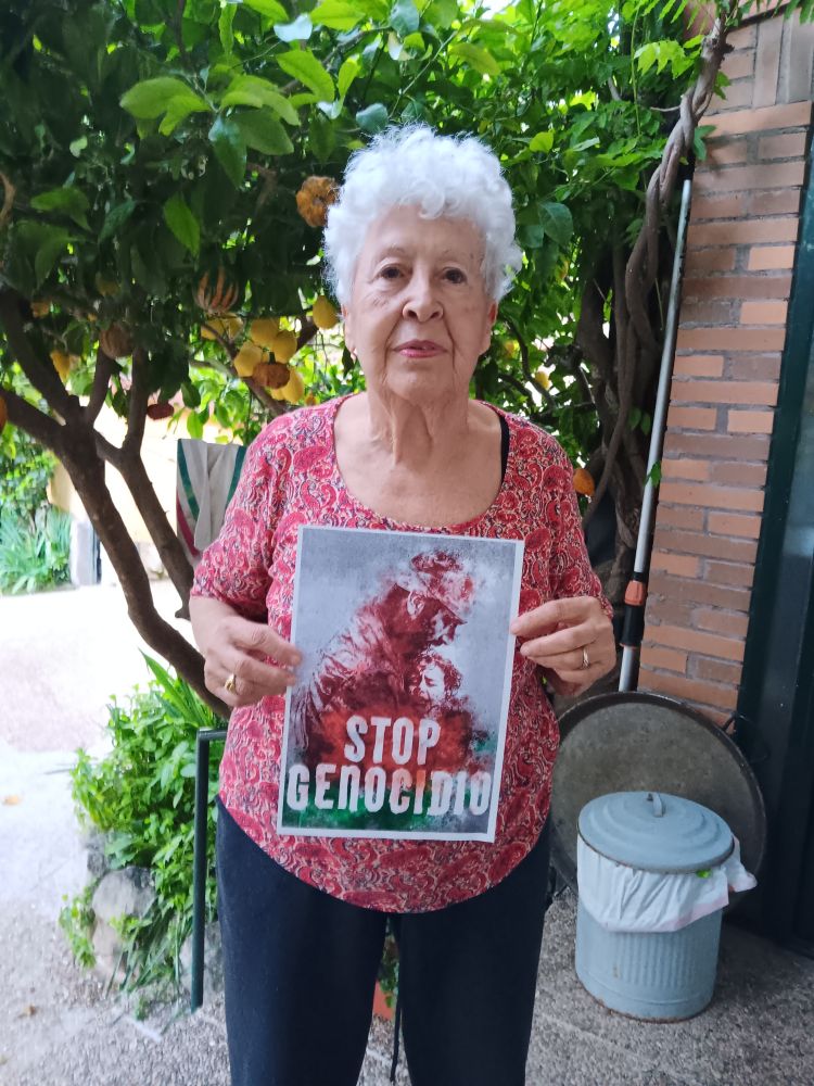 Una mujer sosteniendo un cartel con el lema STOP GENOCIDIO.