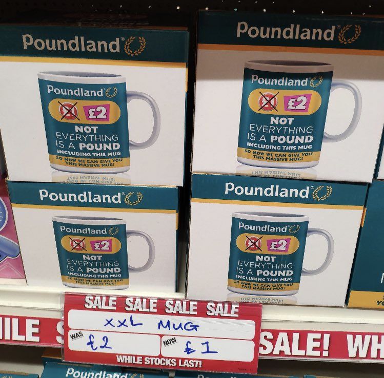 Store shelf at Poundland, where everything is £1. The item for sale is the Poundland "NOT EVERYTHING IS A POUND, INCLUDING THIS MUG, SO NOW WE CAN GIVE YOU THIS MASSIVE MUG!" extra large mug, RRP £2.

The mug is discounted from £2 to £1