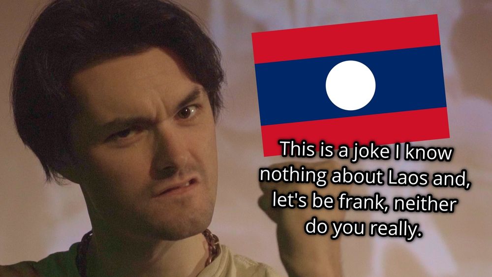 Spice shakes it's fist at the camera. The flag of Laos is on screen with "This is a joke I know nothing about Laos and, let's be frank, nether do you really." written below