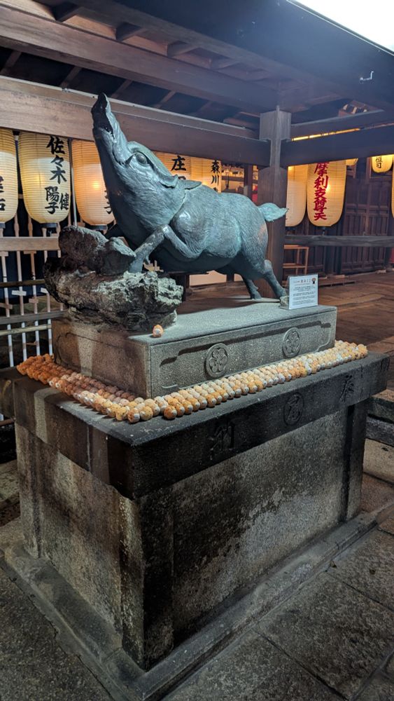 Statue of a boar with little piggy figurines stacked around the base