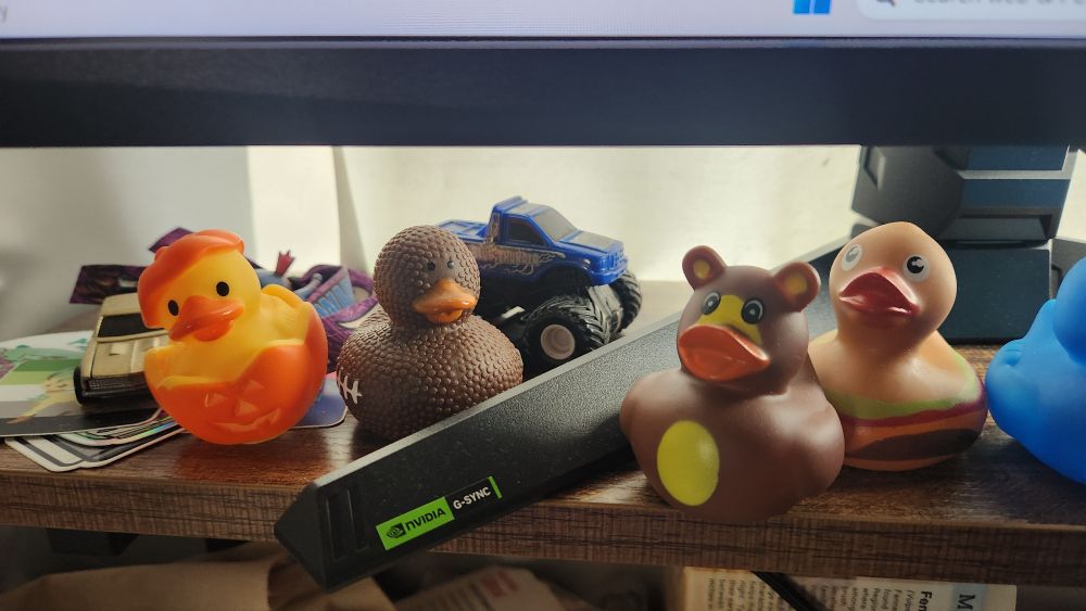 a set of rubber ducks sitting on a desk in front of a monitor stand