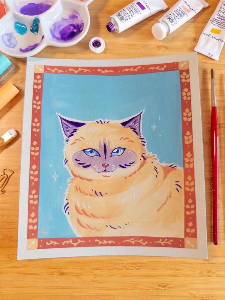 A colorful portrait of a cat made in gouache and posca markers. The cat is beige with purple shadow markings in it's snoot and on it's ears. The drawing is surrounded by traditional art supplies like markers, paint tubes and brushes.