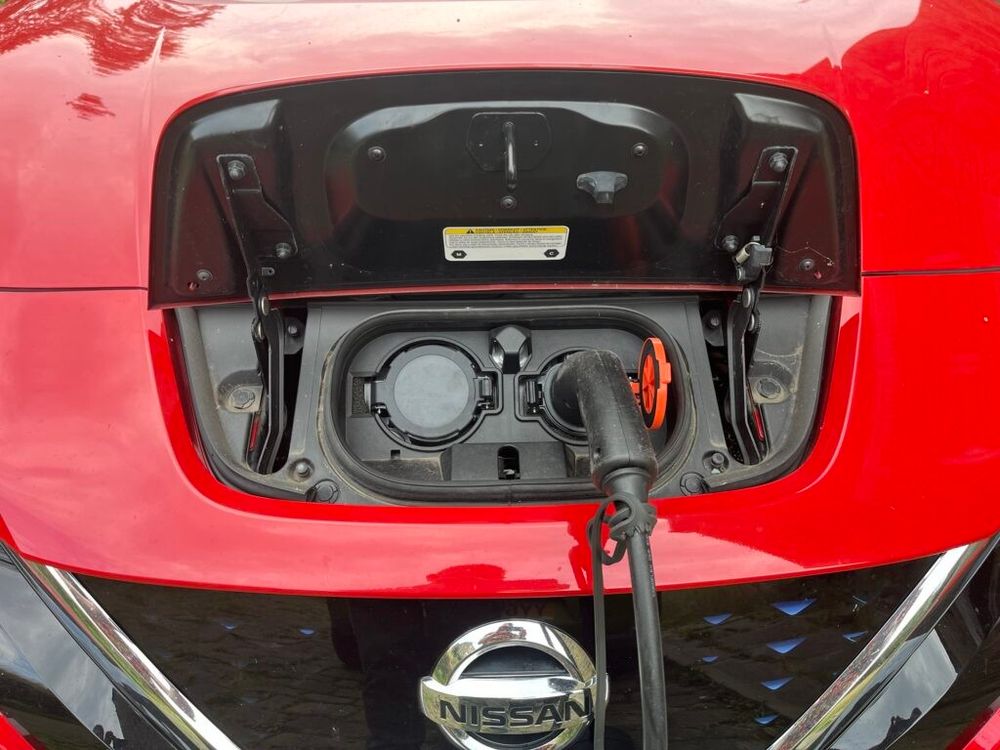 A photo of my Nissan Leaf, with the car charging port open and a Type 2 cable plugged in.