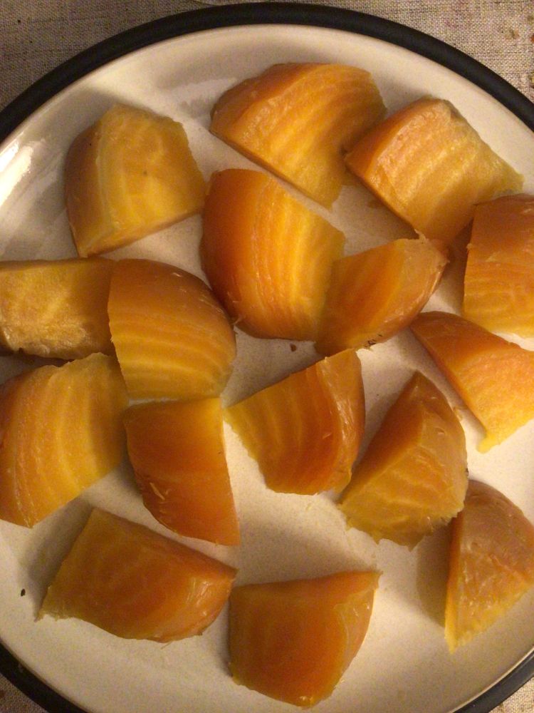 Two golden beets cut into eighths on a dinner plate