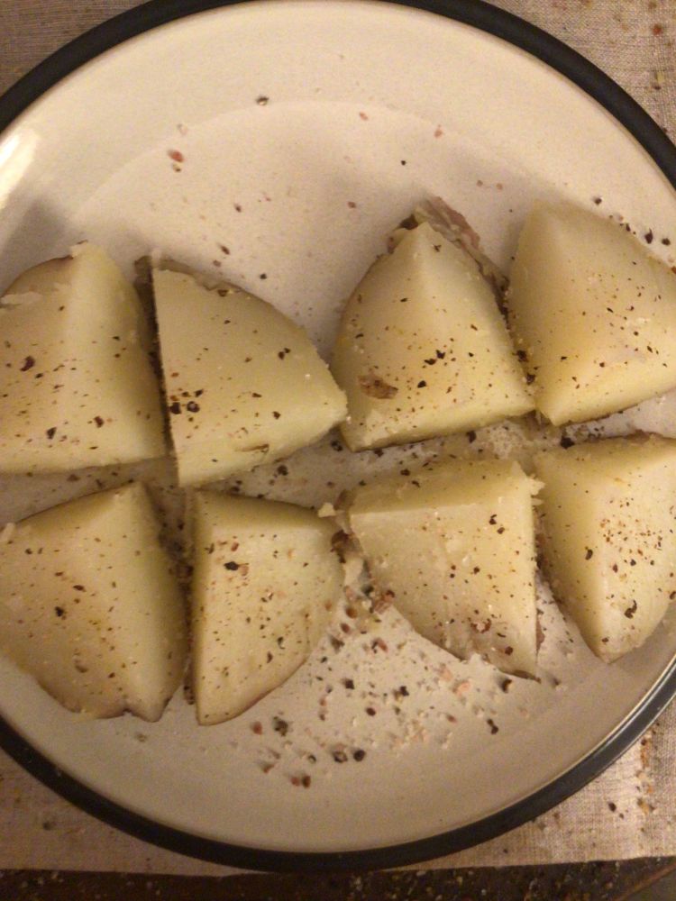 A red potato cut into eighths and seasoned with salt and pepper on a dinner plate