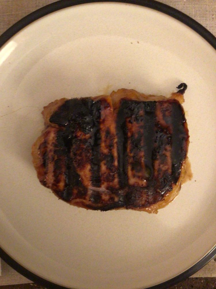 A curried mango boneless pork chop on a dinner plate