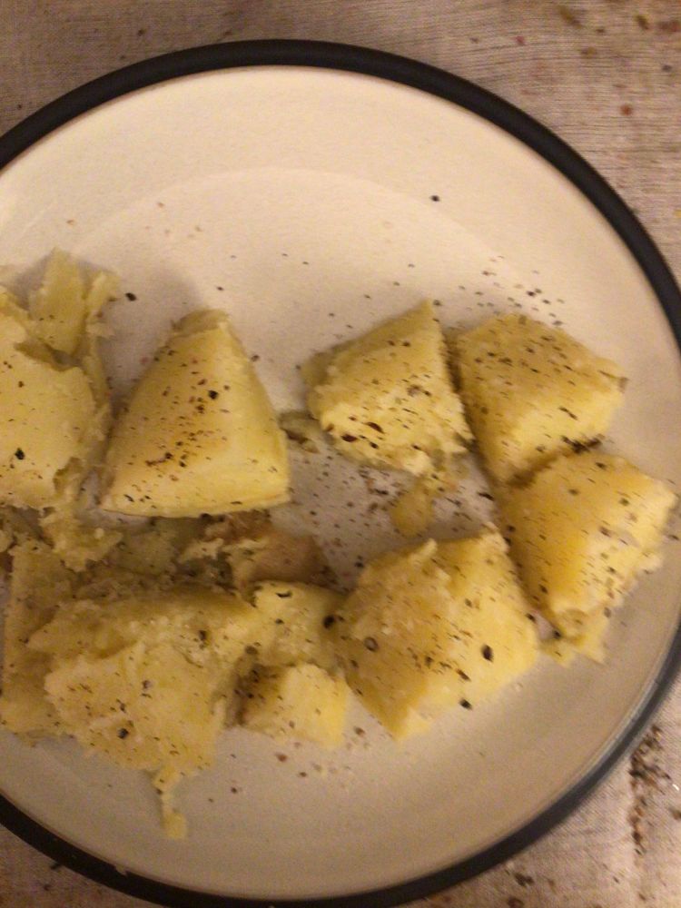 A medium Yukon gold potato cut into eighths and seasoned with salt and pepper on a dinner plate
