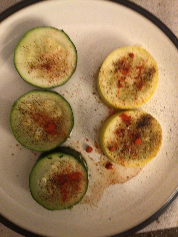 A combination of zucchini and yellow squash seasoned with black garlic and paprika on a dinner plate