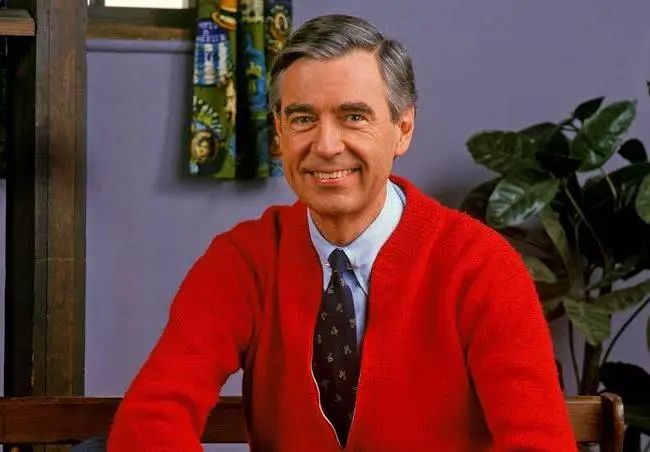 a photo of a smiling Fred Rogers in a red cardigan 