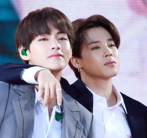 Taehyung and Jimin standing close. Jimin has his arm around Taehyung's shoulder.