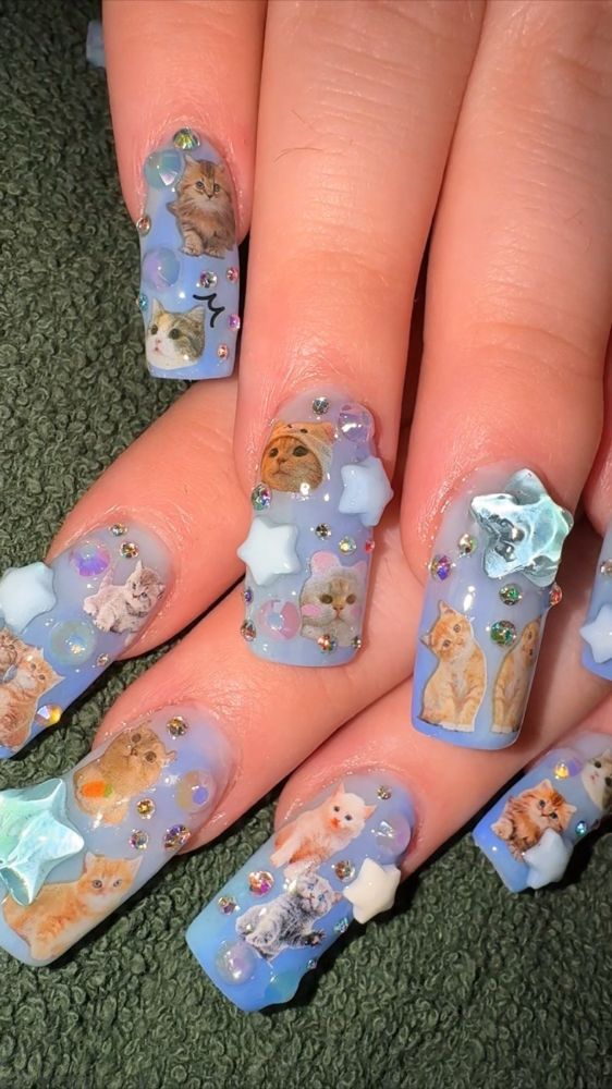a long square pastel blue manicure with adorable kittens stickers and chunky star charms 