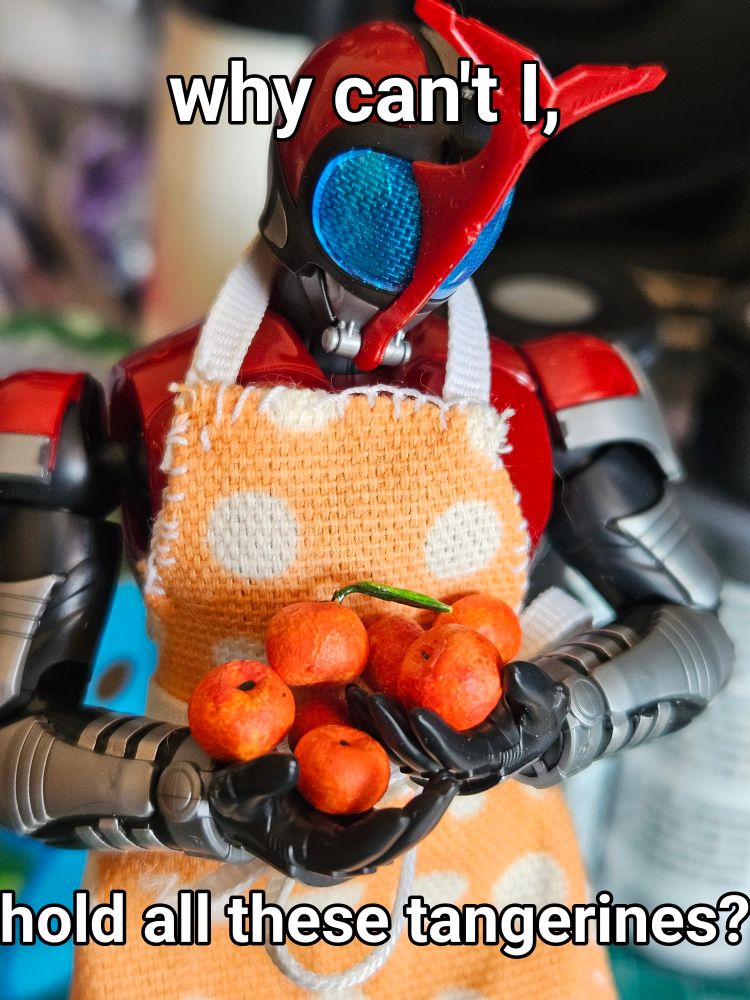 An action figure holding a large number of scale tangerines. Text says "Why can't I, hold all these tangerines?"