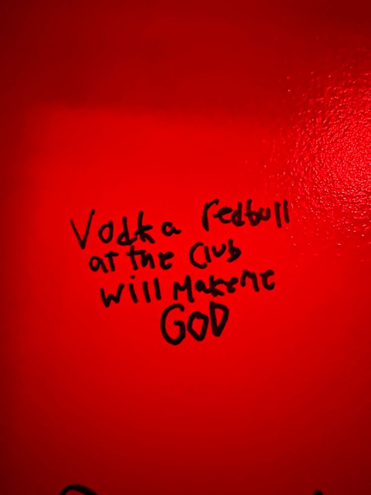 Bathroom graffiti that says "Vodka redbull at the club will make me GOD"