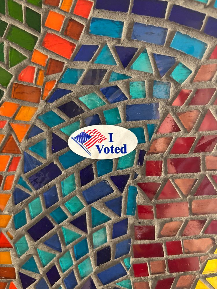 "I voted" sticker on a colorful mosaic background.