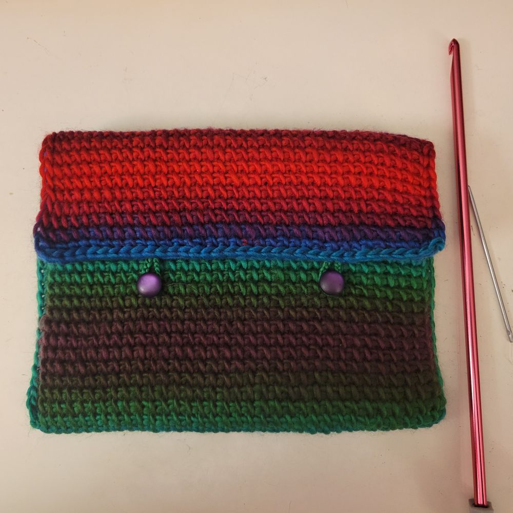 A crocheted bag about the size of a DVD case in a variety of jewel tone colors.