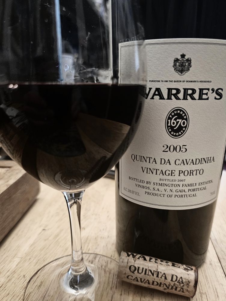 A glass of Warre's 2005 Quinta da Cavadinha Port with its bottle and cork. From Portugal, Douro