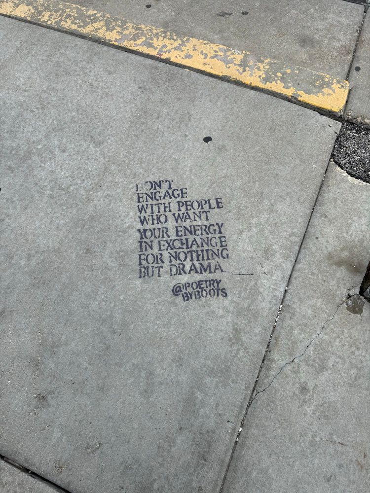 A photo of a cement sidewalk with the words “don’t engage with people who want your energy in exchange for nothing but drama @poetrybyboots” spray painted with a stencil on it 