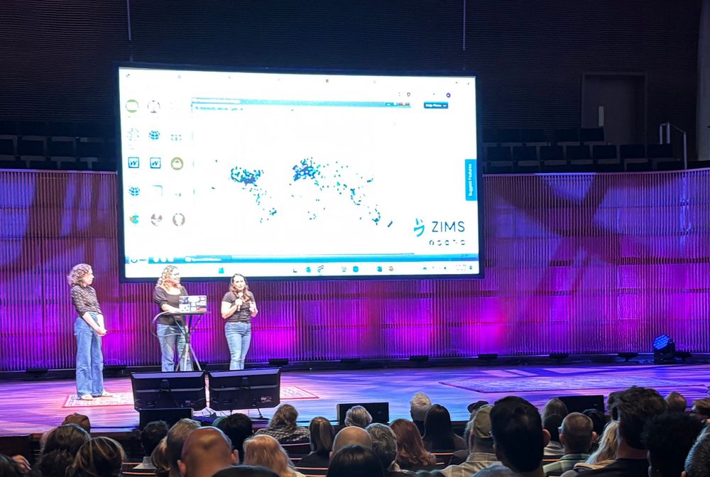 Three women with a species world map on a projector behind them
