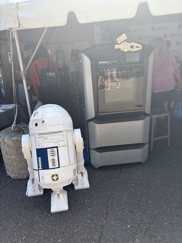 3D printer and a life size 3d printed R2D2 in a tent outdoors