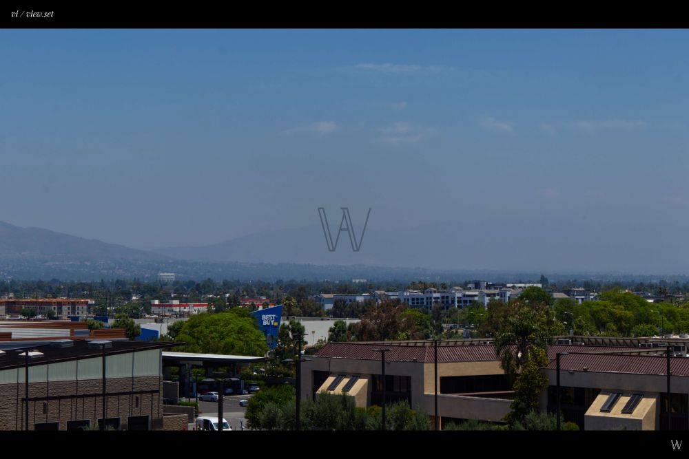A cool color photo of Woodland Hills in Los Angeles, California with shopping centers and homes running till you hit the mountain.