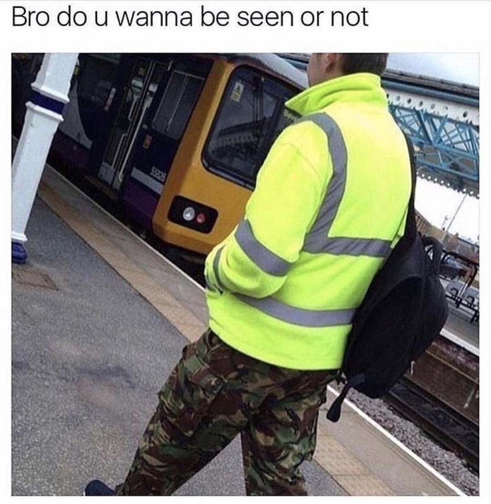 Photo of a man wearing a high visibility jacket and camouflage printed trousers with the caption "bro do you want to be seen or not" 