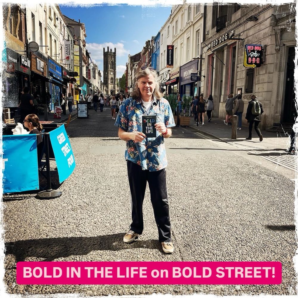 Me holding a copy of my book in the middle of Bold Street 