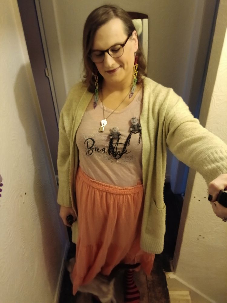 Me wearing lightning bolt rainbow earrings and a pink skirt and a Marley and Marley brooch OMG wow! Also, a kitten is messing with my skirt in this one.