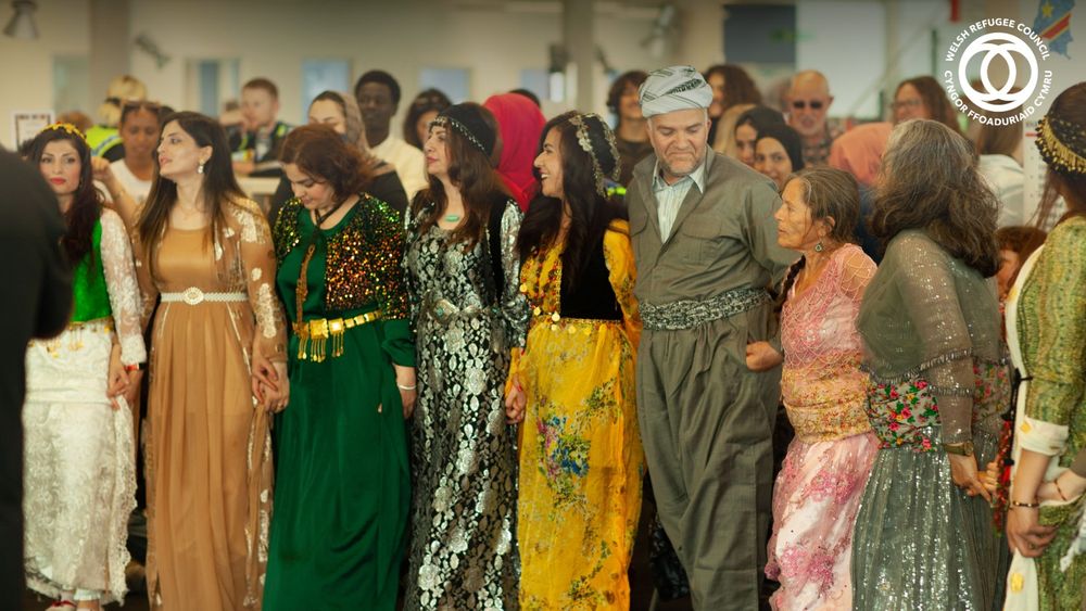 A group of people holding hands and celebrating Refugee Week together.