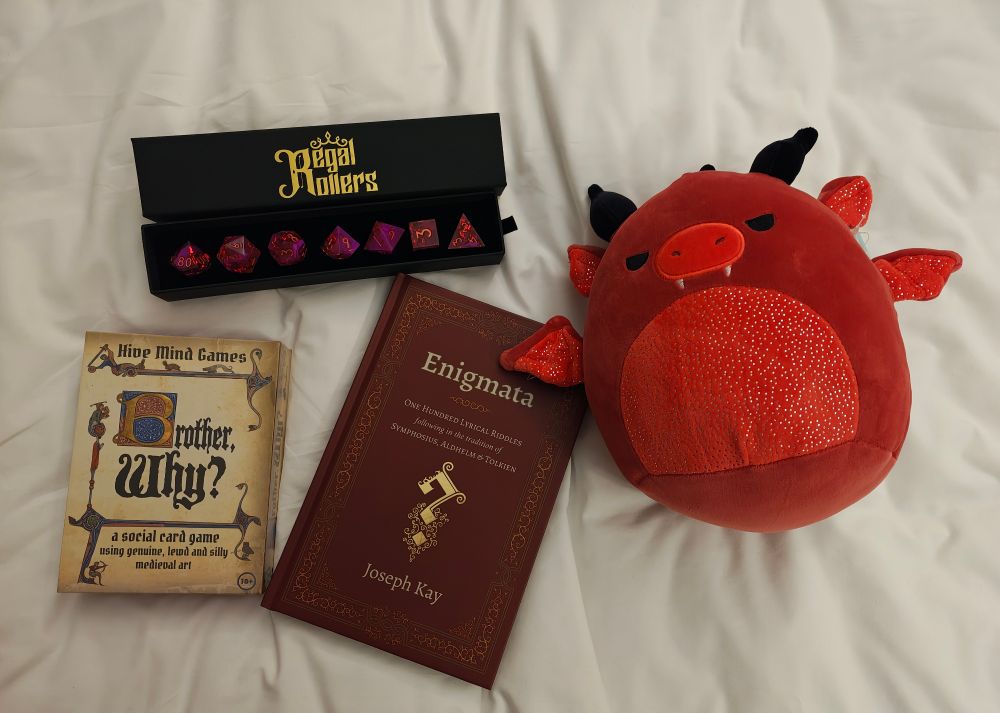 1. A set of rose coloured dice from Regal Rollers. 
2. A card game called Brother, Why? By Hive Mind Games
3. A book of riddles called Enigmata by Joseph Kay
4. A red dragon Squishy toy
