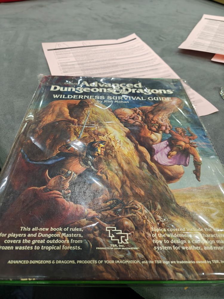 A photo of a 1st edition version of the AD&D Wilderness Survival Guide by Kim Mohan. 

This (not all-new) book of rules for players and Dungeon Masters. It covers the great outdoors from frozen wastes to tropical forests. Topics covered include the effects of the wilderness on characters, how to design a campaign map, a system for weather, and more! 