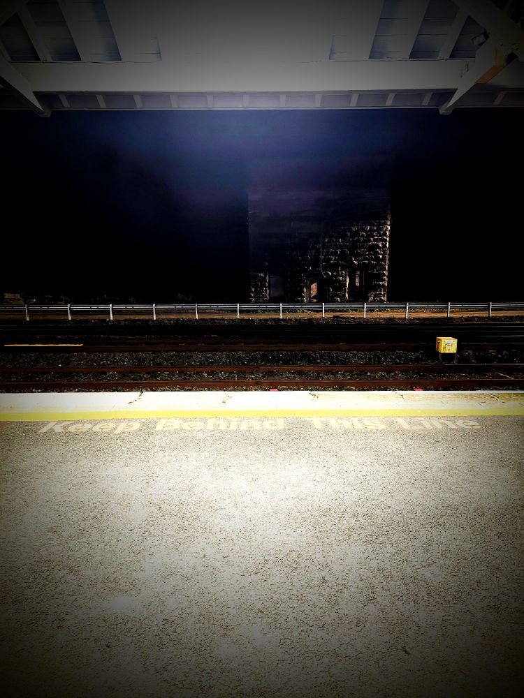 A photo of the train platform at Limerick junction. It is night. The words Keep Behind This Líne can be seen. 