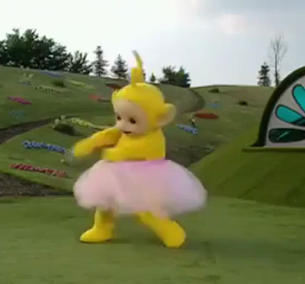 a teletubbies character is wearing a pink tutu and dancing in a field .