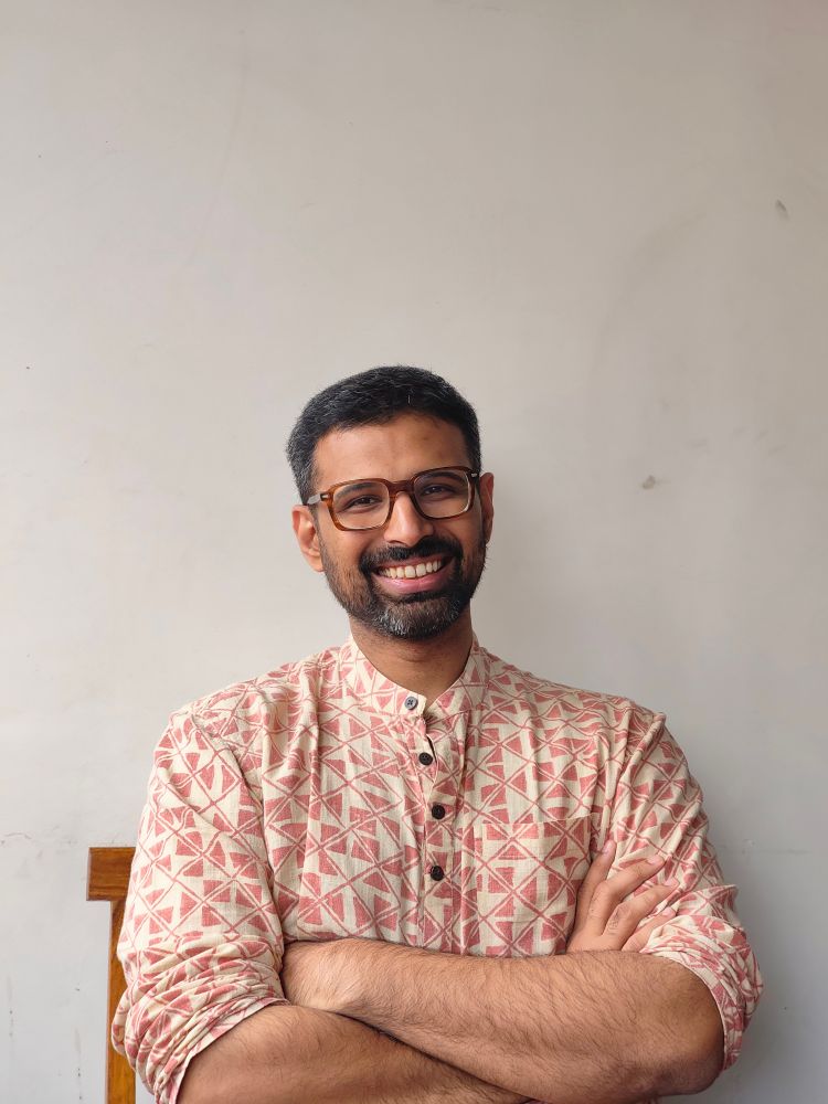 Me, smiling, sitting on a chair, arms crossed