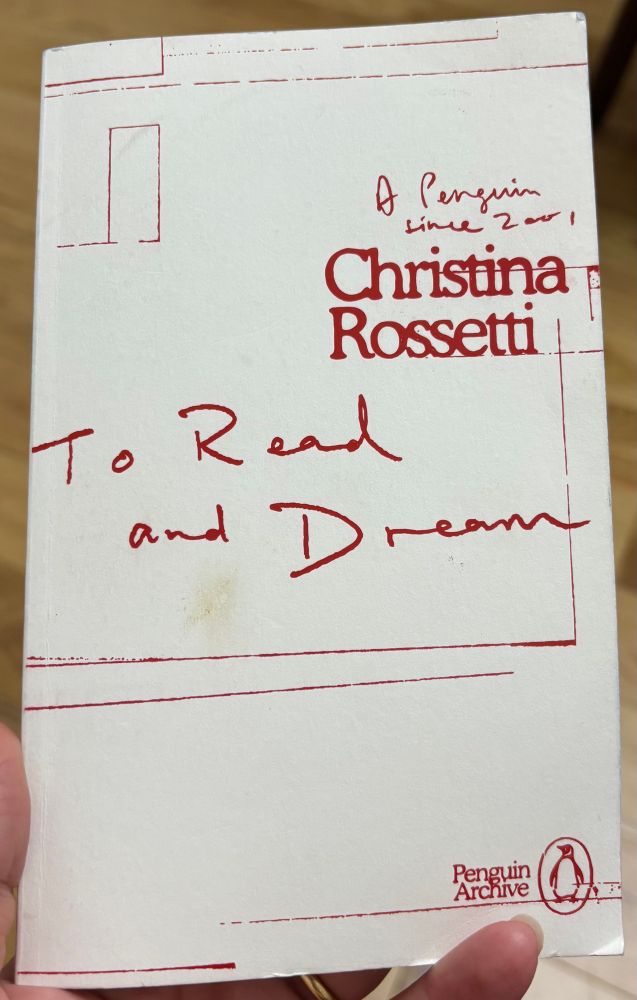 The book cover of the Penguin Archive version of To read and Dream by Christina Rossetti. It is a white cover with a gorgeous read hand written title & red line drawing. Detracted from slighted by a big smudge of tomato leaf residue I have managed to thumbprint onto it. 
