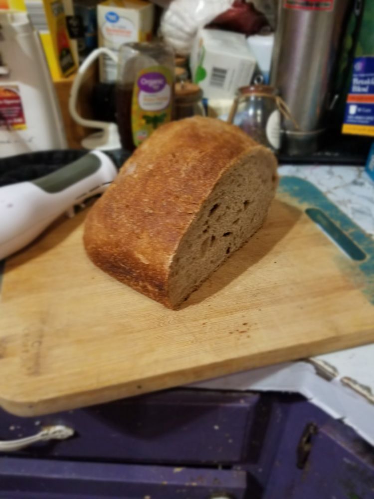 Big square loaf of whole-wheat sourdough. About half a loaf is left and it's just starting to turn stale. messy countertop