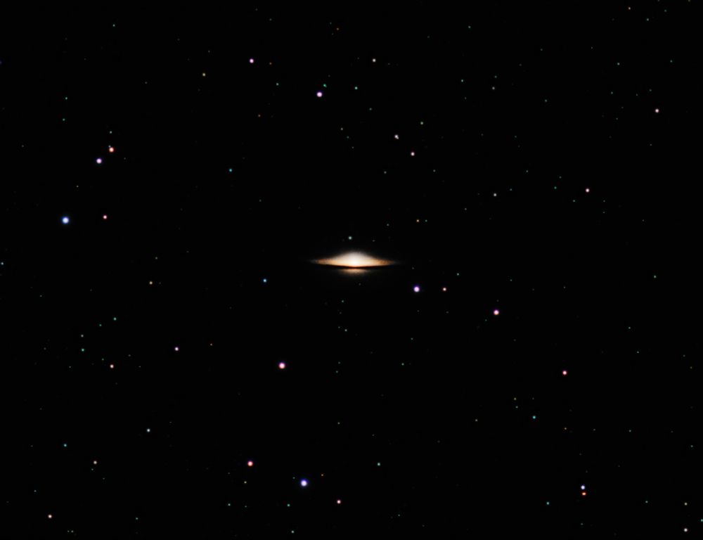 This is a photograph of M104, the Sombrero Galaxy, seen edge-on from Earth. With its thick bulge and resemblance to a hat, it resembles a hat. Numerous stars of various colors and brightness litter the scene.