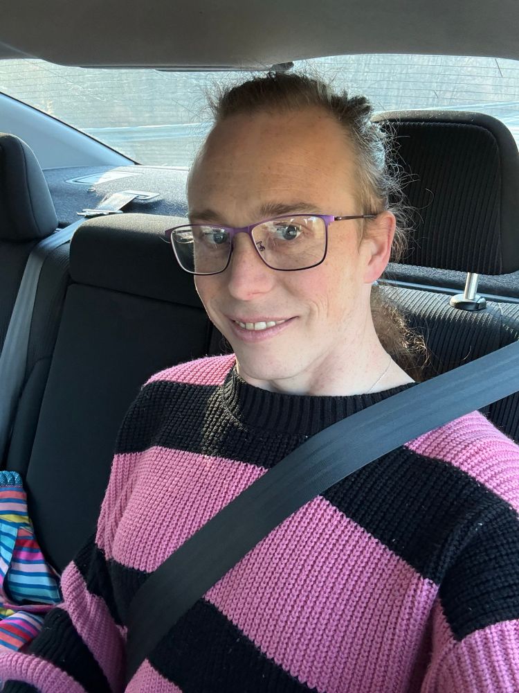 Allison in a pink and black striped sweater and glasses