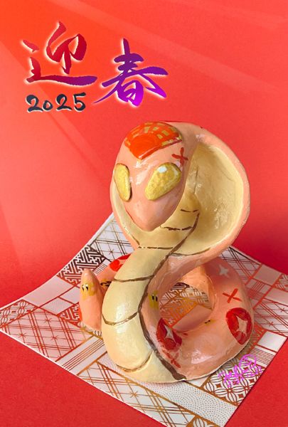 巳年にちなんだピンク色の蛇の像が和柄の紙の上に乗っています。