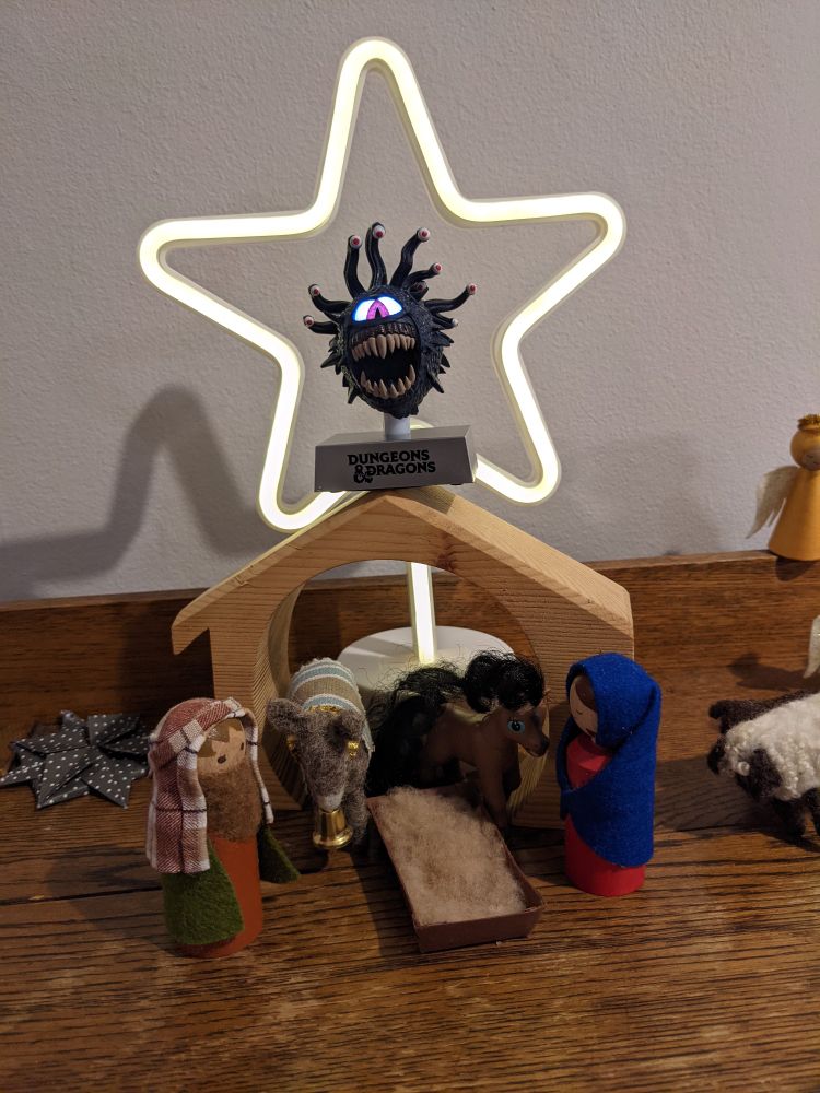 a miniature nativity scene with Mary, Joseph, a donkey, a plastic toy horse, and a beholder balanced on the top of the stable.