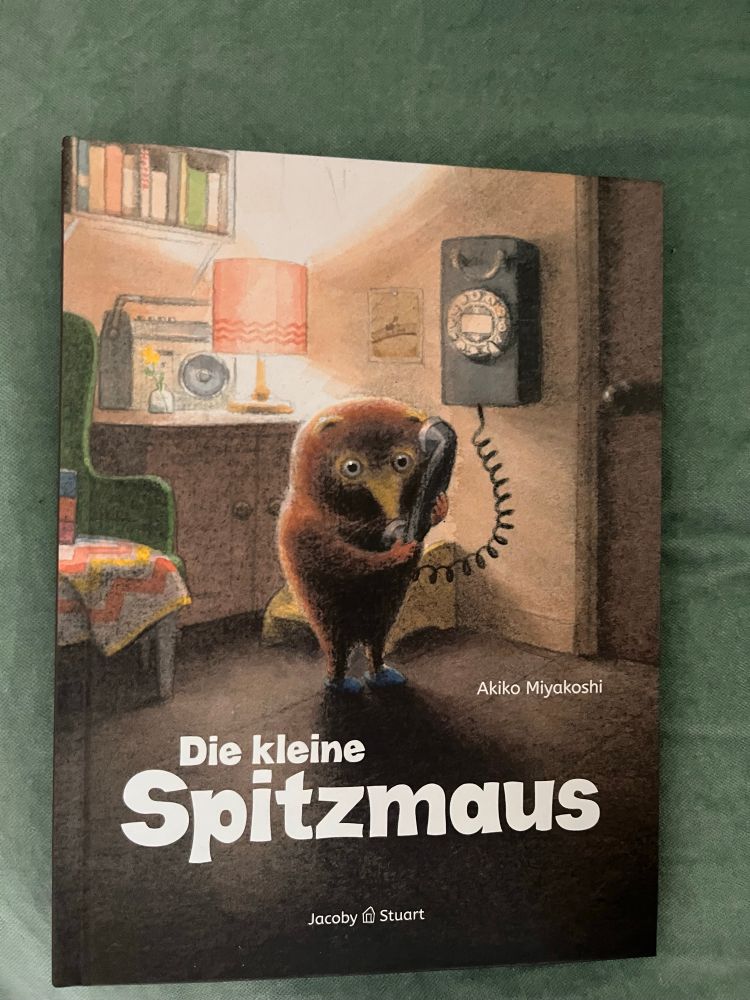 Ein kleines Bilderbuch von Akiko Miyakoshi, erschienen bei Jacoby und Stuart. Es heißt die kleine Spitzmaus. Auf dem Cover steht jene kleine Spitzmaus telefonierend in ihrer kleinen Wohnung.
