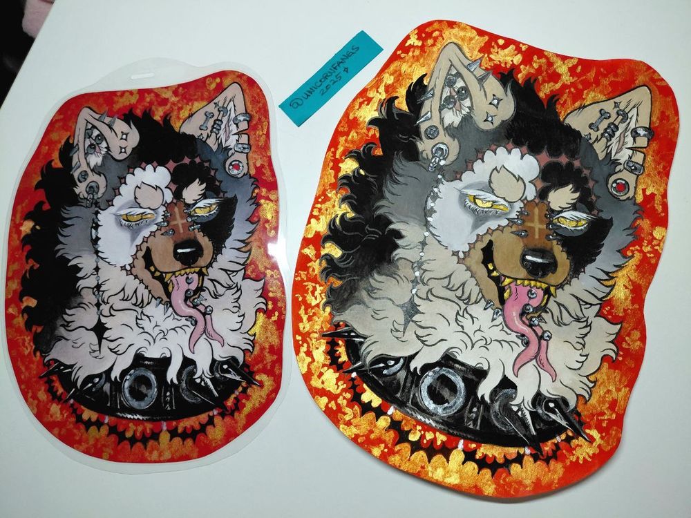 Two sona badges sitting on a desk. Left is badge copy, right is original painting!