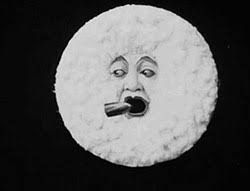 a very fluffy moon with a shocked face, about to accidentally swallow a bullet-shaped rocket; still from the 1908 unauthorized remake of george melies 1903 film voyage dans la lune, called excursion dans la lune.